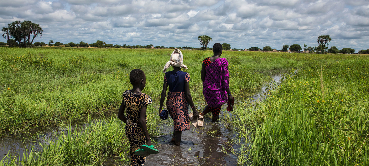 WFP/Gabriela Vivacqua A woman and her family wade through a flooded plain to reach their home in Thaker, Unity state, South Sudan.